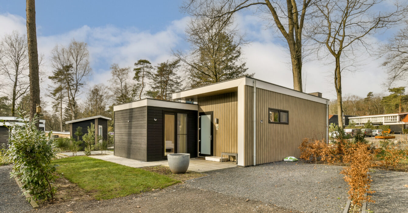 a small wooden house with a gravel driveway and trees a small wooden house with a gravel driveway and trees