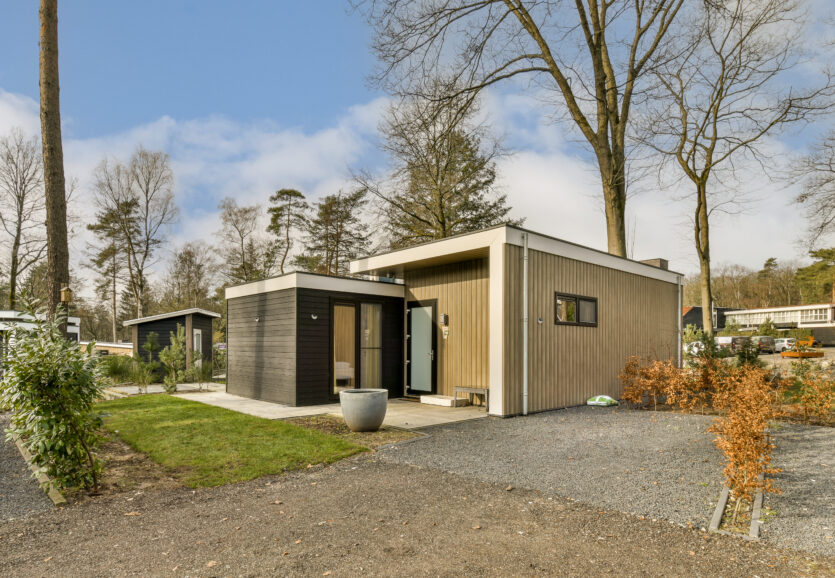 a small wooden house with a gravel driveway and trees